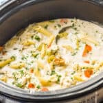 side view of a slow cooker full of creamy crockpot chicken noodle soup with the title of the recipe for a pinterest graphic