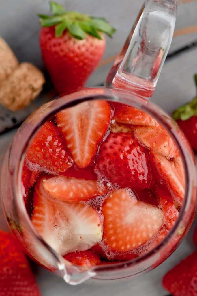 overhead of a pitcher of rose sangria filled with strawberries