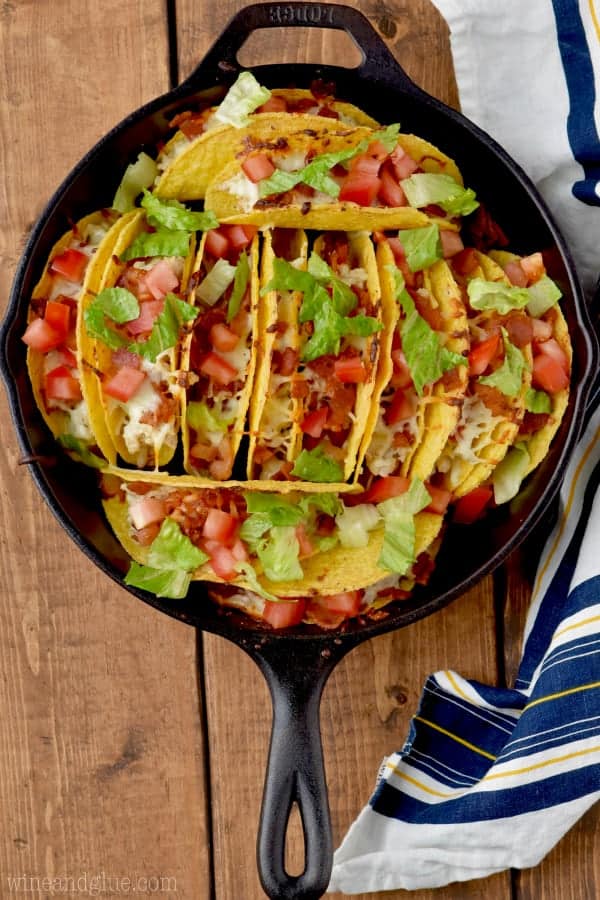An overview photo of the Creamy BLT Ranch Oven Baked Tacos stuffed in a skilled and topped with diced tomatoes and lettuce. 