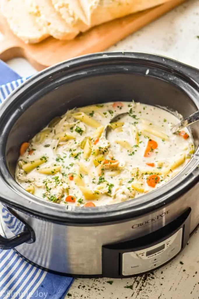 side view of a slow cooker full of creamy crockpot chicken noodle soup
