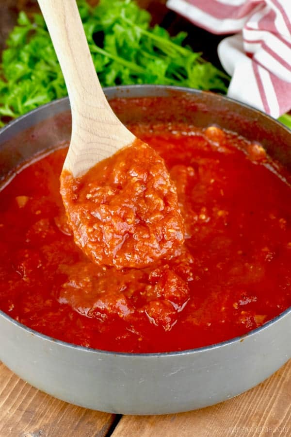 In a small pan, a wooden spoon is stirring the Easy Homemade Spaghetti Sauce. 