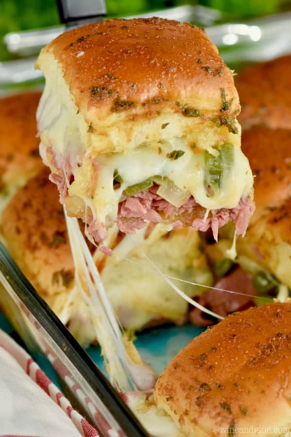 A Philly Cheesesteak Sliders is being lifted out of the casserole dish causing some cheese pull