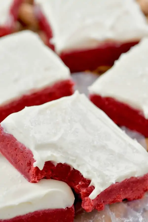 A close up photo of the Red Velvet Bars topped with white frosting and has a little bite. 