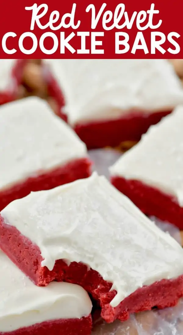 A closeup photo of the Red Velvet Bars with a small bite and topped with white frosting and clear sprinkles. 