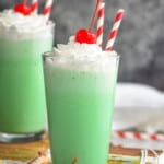two tall tumblers filled with shamrock shakes, topped with whipped cream and a cherry - 8