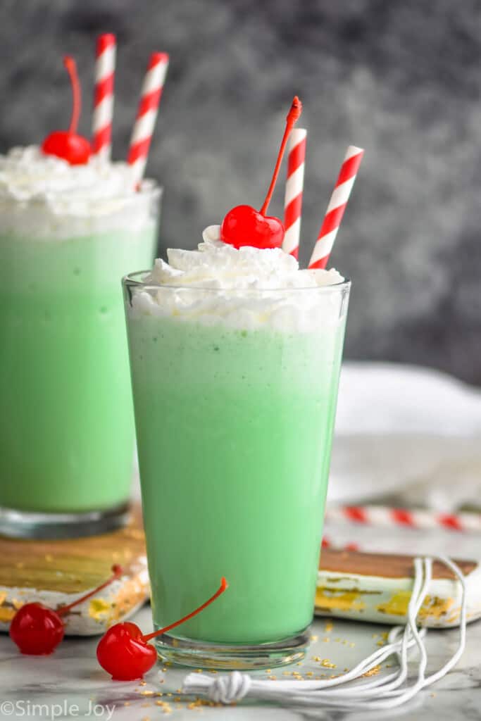 two tall tumblers filled with shamrock shakes, topped with whipped cream and a cherry