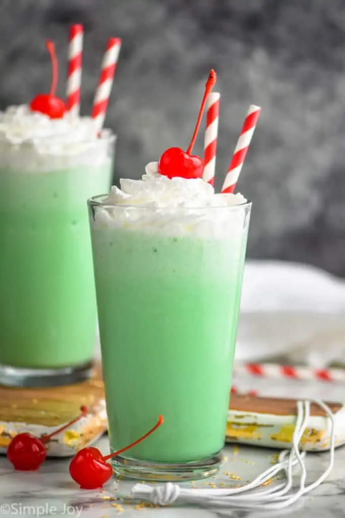 two tall tumblers filled with shamrock shakes, topped with whipped cream and a cherry