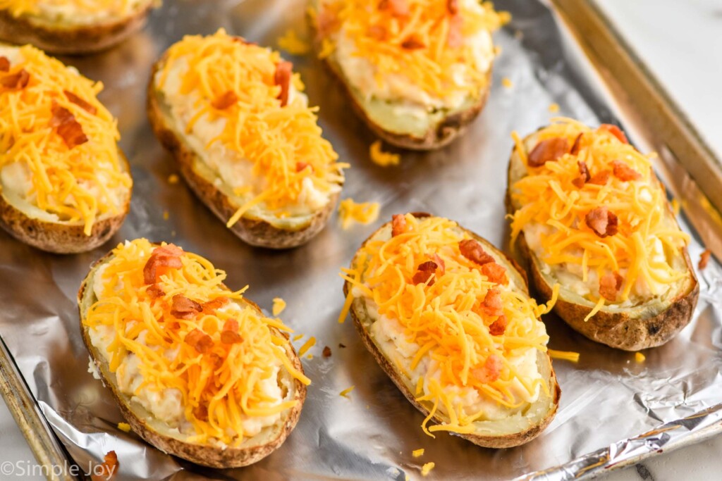 twice baked potatoes on a baking sheet filled and ready to go in the oven one last time