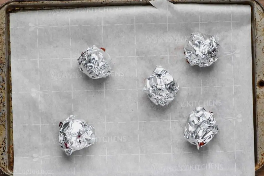 baking sheet lined with parchment paper with foil wrapped beets on it