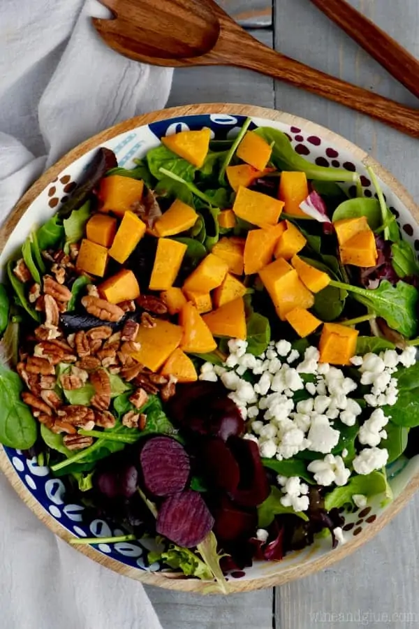 A overhead photo of Roasted Beet Salad with cubbed butternut squash, pecans, goat cheese, mixed greens, and roasted beats.  