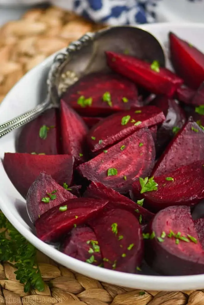 white bowl full of roasted beets recipe and antique spoon, garnished with fresh parsley