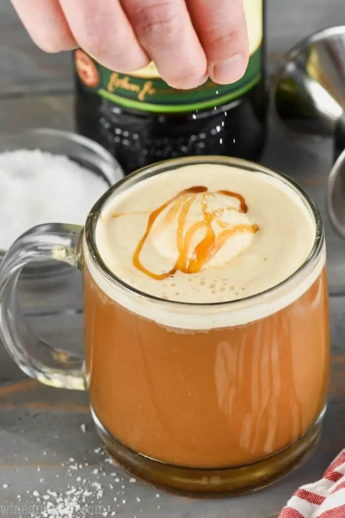 a sprinkle of kosher salt being added to a salted caramel Irish coffee recipe