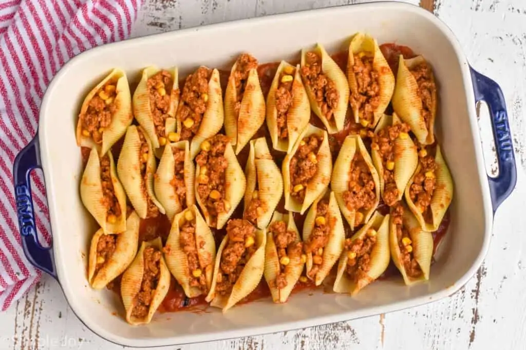 overhead of a pan of pasta shells stuffed with taco filling before they are covered with salsa and cheese