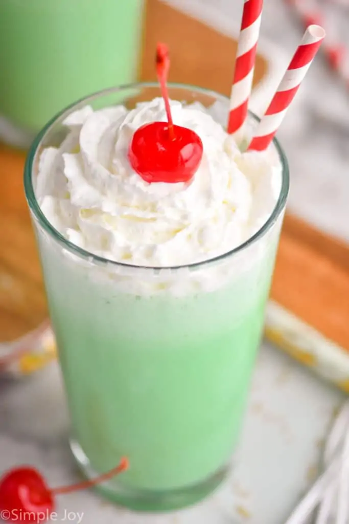 close up overhead of a tumbler filled with McDonald's shamrock shake, topped with whipped cream and a cherry