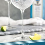Pinterest graphic of the perfect gin and tonic recipe. Image is photo of glasses of gin and tonic garnished with lime wedges. Text says, "The best gin and tonic simplejoy.com"