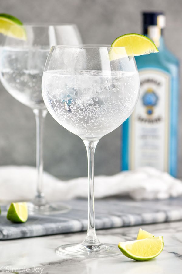 Glass of the perfect gin and tonic recipe garnished with a lime wedge.