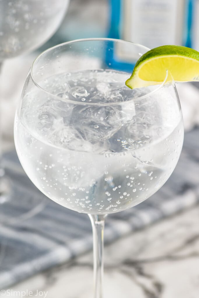 Glass of the perfect gin and tonic recipe garnished with a lime wedge.