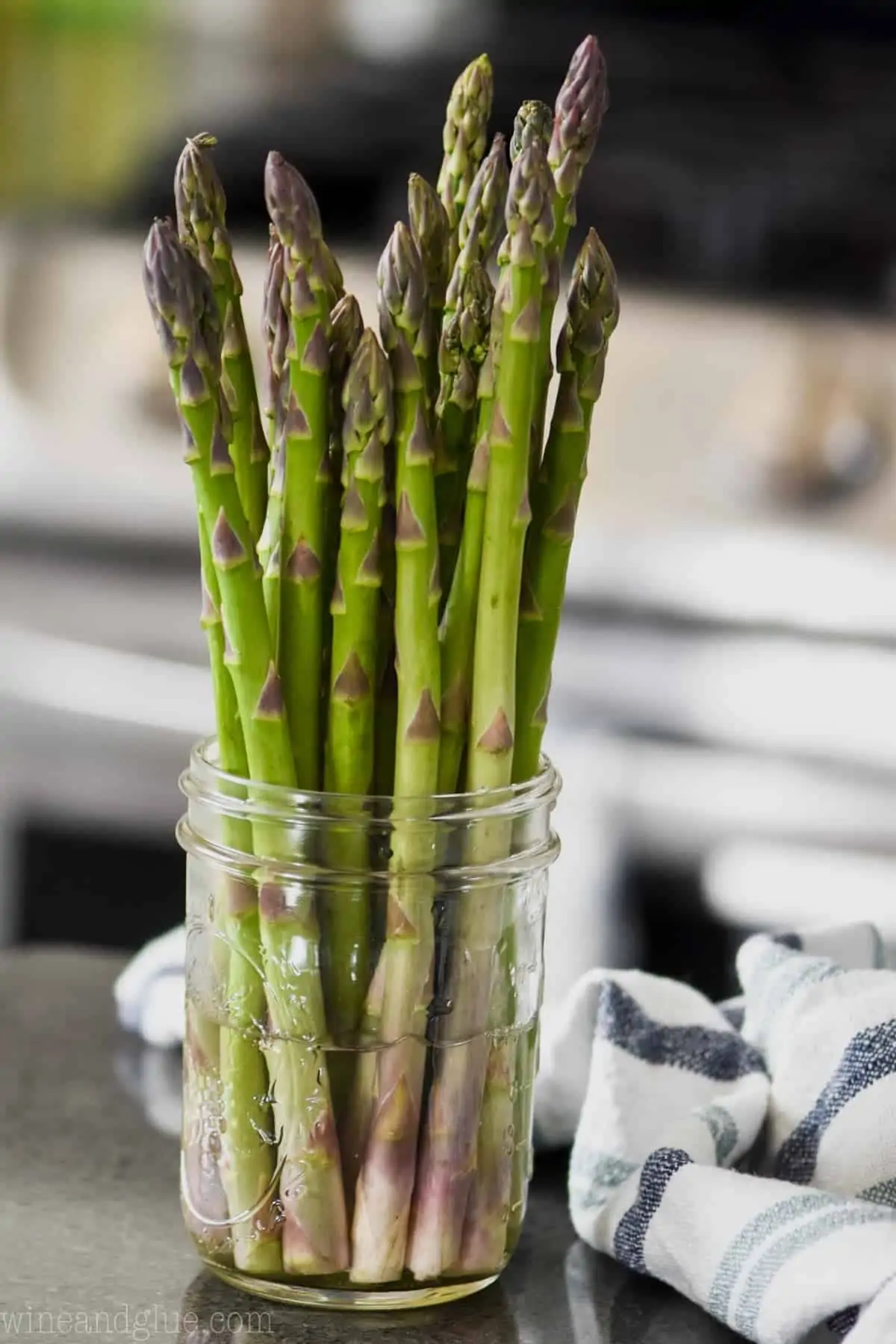 bunch of asparagus in a mason jar with a little water to store in the refrigerator