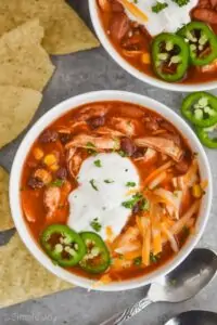 overhead view of a bowl of instant pot taco soup garnished with sour great, shredded cheese, and freshly sliced jalapeños