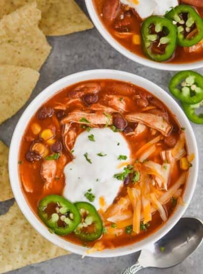 overhead view of a bowl of instant pot taco soup garnished with sour great, shredded cheese, and freshly sliced jalapeños