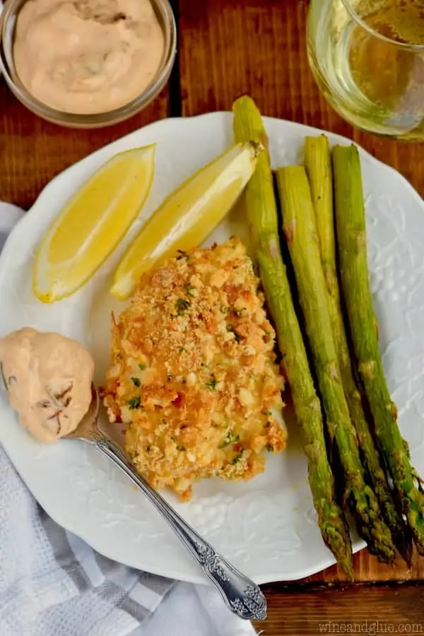 fish, asparagus, lemons, and chipotle horseradish sauce on a white plate