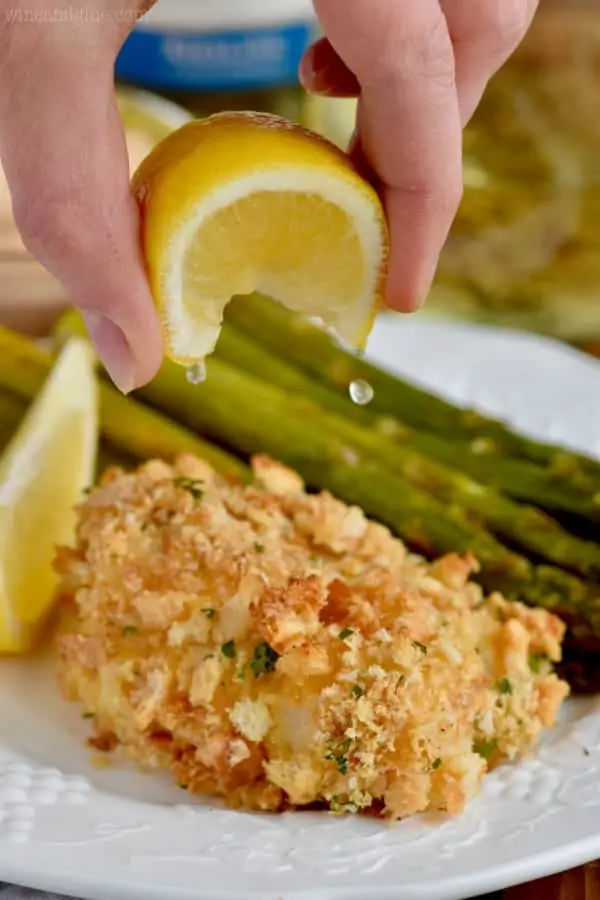 lemon being squeezed on oven fried fish on a plate