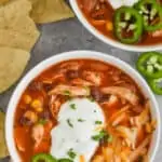 overhead view of a bowl of instant pot taco soup garnished with sour great, shredded cheese, and freshly sliced jalapeños