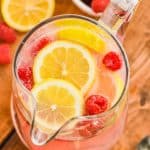 overhead view of a pitcher of pink lemonade vodka punch floating with fresh lemons and fresh raspberries - 11