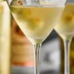 straight on view of a frosted martini glass with a dirty martini in it, garnished with three olives