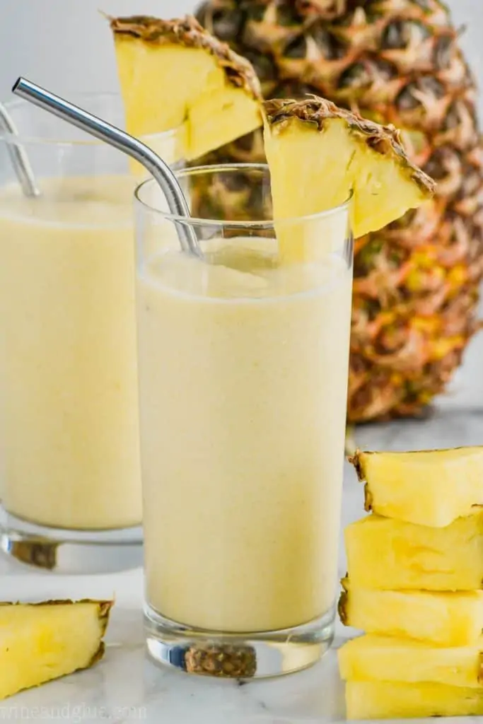 glass of vanilla dole whip with metal straw and pineapple garnish