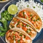 overhead view of three instant pot chicken tacos on a plate with cilantro lime rice