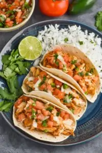 overhead view of three instant pot chicken tacos on a plate with cilantro lime rice