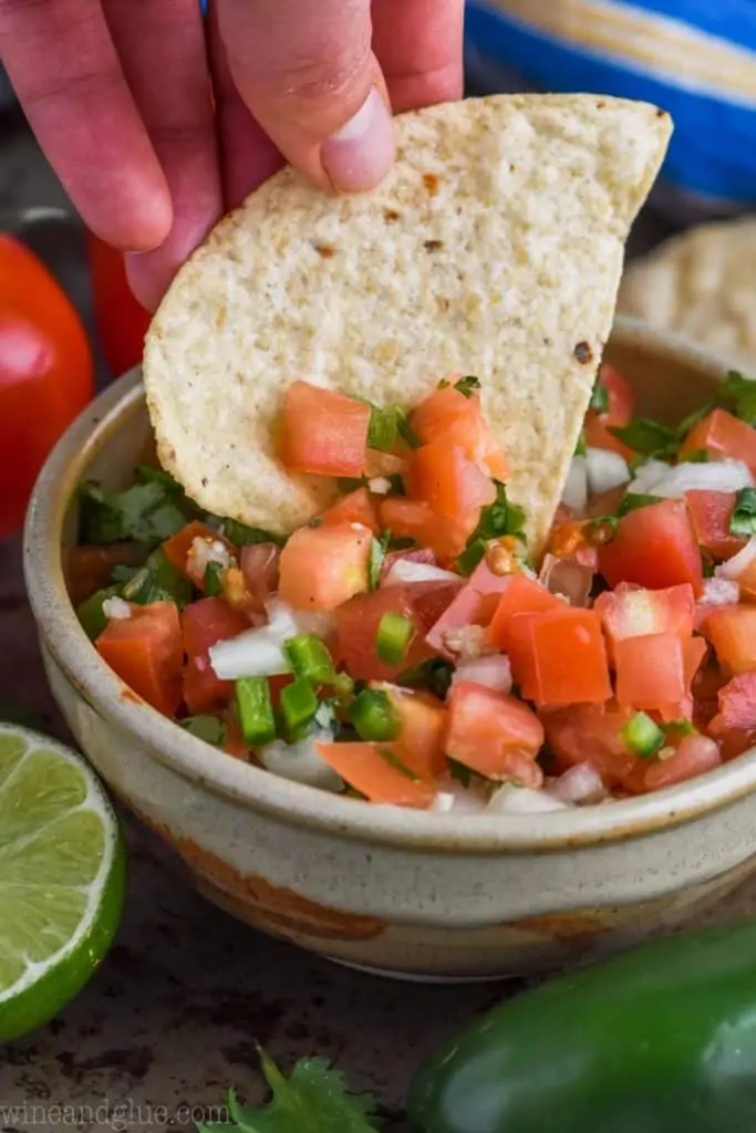 a tortilla chip dipping into pico de gallo recipe