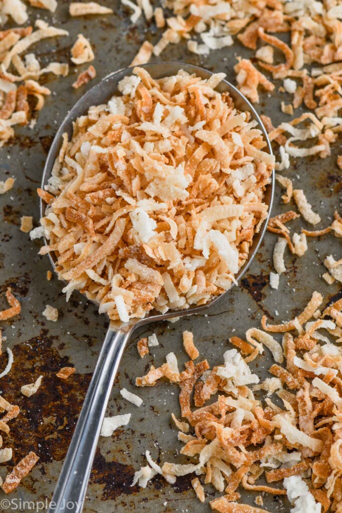 serving spoon full of toasted coconut on a baking tray