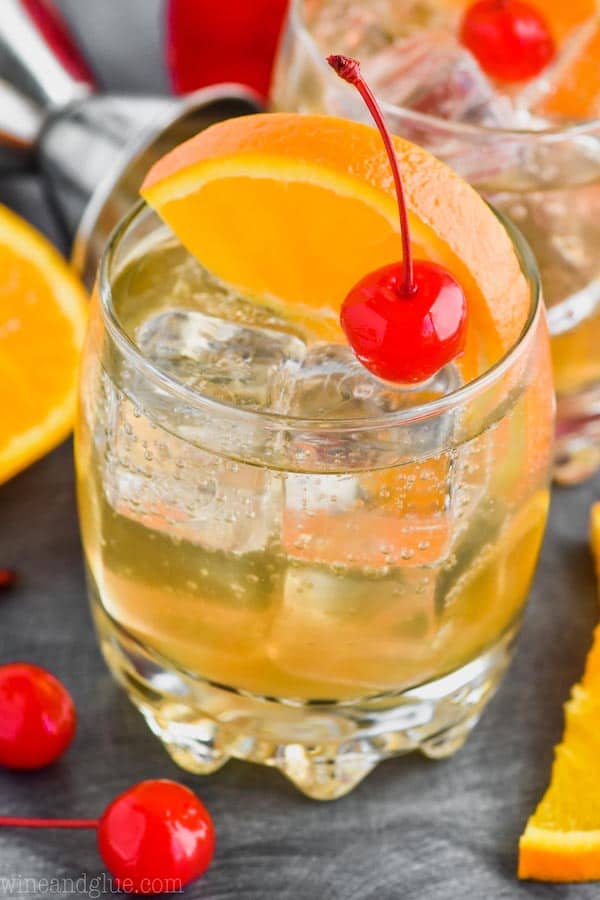 an amaretto sour recipe in a glass with a cherry and orange