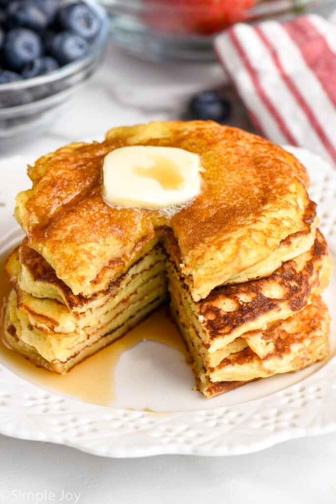 stack of yogurt pancakes with butter and syrup on top, a wedge cut out of them