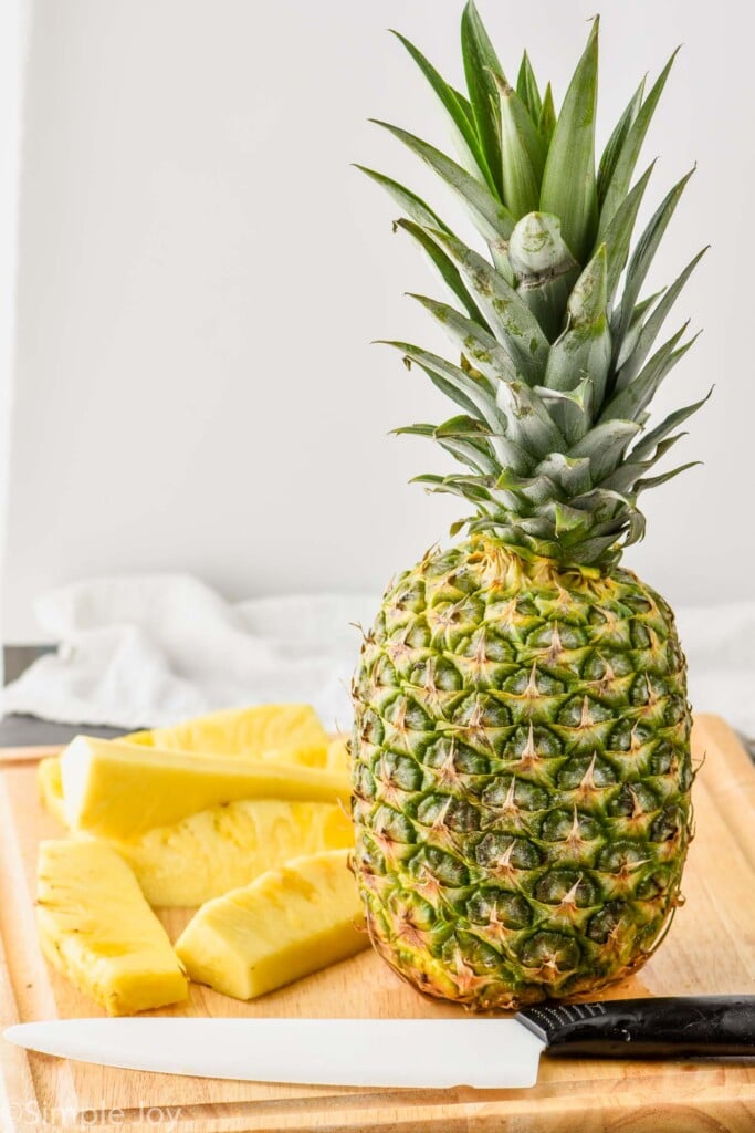 a whole pineapple on a cutting board waiting t be cut