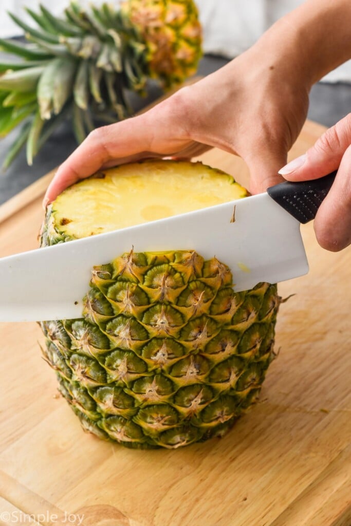 a pineapple on a cutting board with the skin being cut off