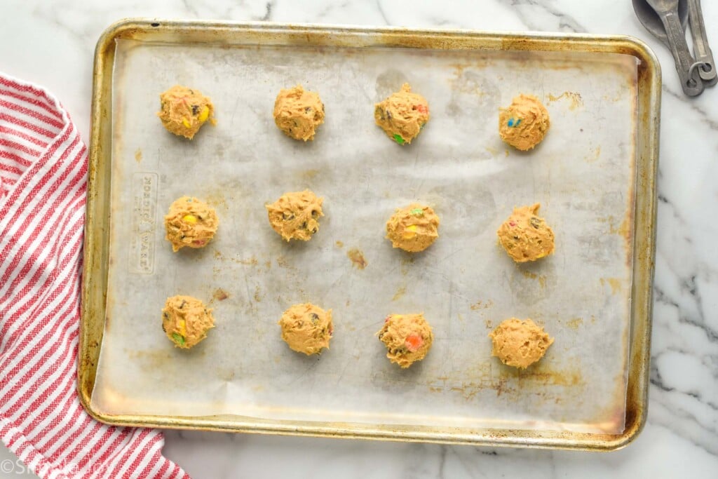 Overhead photo of Monster Cookies recipe dough balls on a baking sheet before baking.