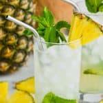 high ball glass filled with ice and a pineapple mojito, garnished with mint and a pineapple wedge