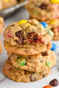 Close up photo of a stack of Monster Cookies with a bite taken out of the top cookie.