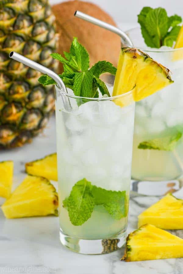 high ball glass filled with ice and a pineapple mojito, garnished with mint and a pineapple wedge