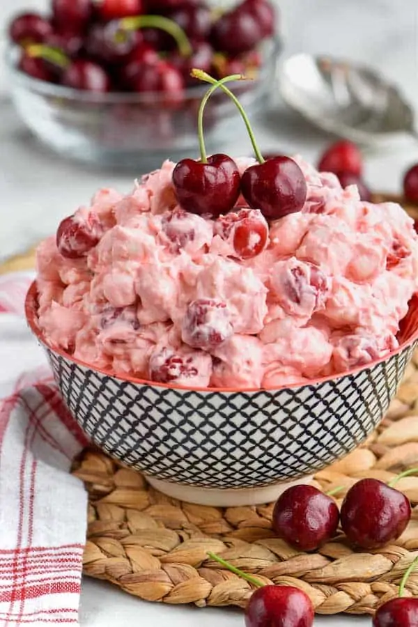 a bowl of cherry cheesecake fluff topped with fresh cherries