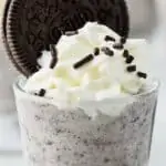 up close shot glass of cookies and cream pudding shots garnished with whipped cream and an oreo