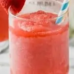 frosted glass of rose with two straws garnished with a strawberry