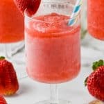frosted glass of rose with two straws garnished with a strawberry