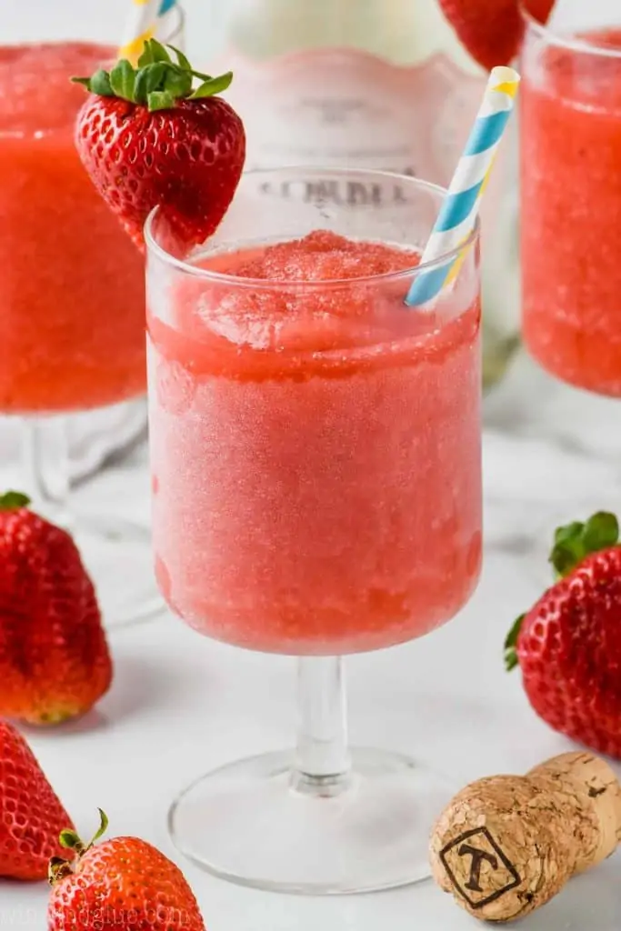 frosted glass of rose with two straws garnished with a strawberry