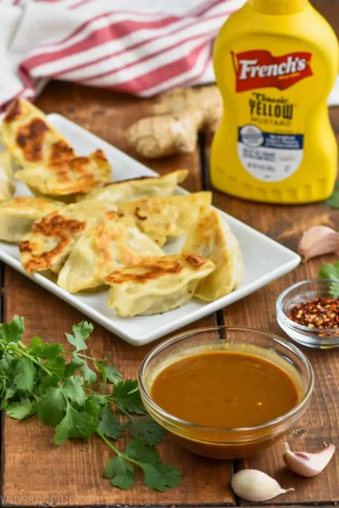 small bowl of potsticker sauce with potstickers in the background