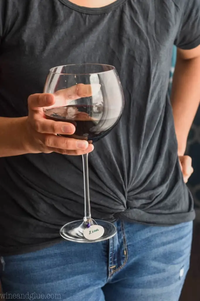 woman holding a red wine glass with a diy wine charm on it