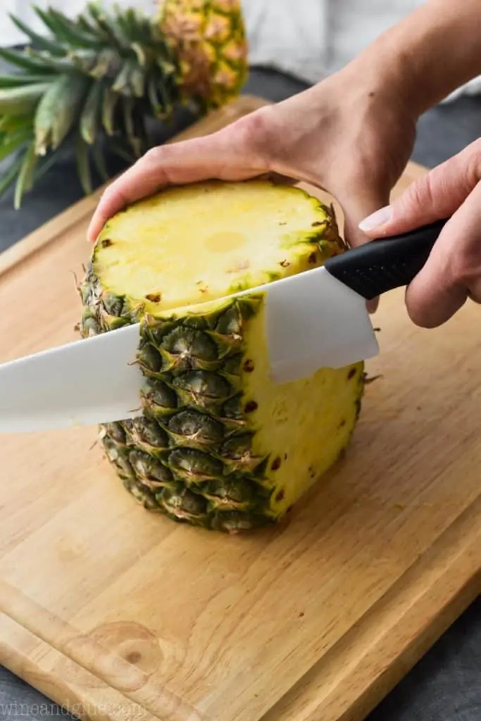 a pineapple on a cutting board with the skin being cut off